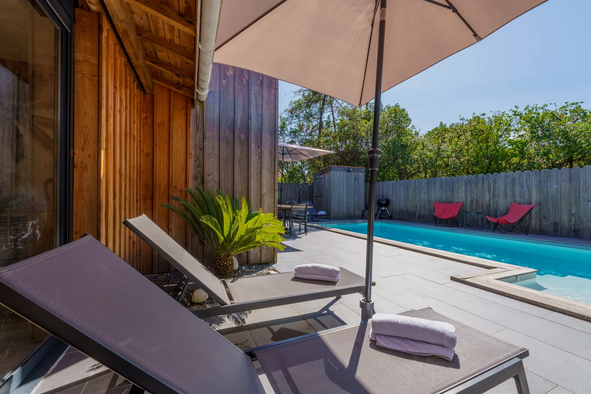 Transats sous parasol au bord de la piscine