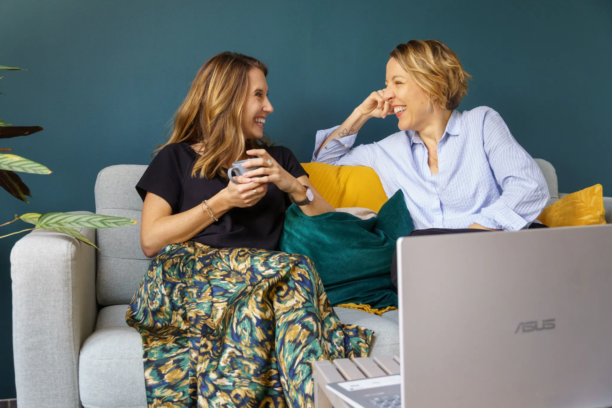 Deux collègues discutant autour d'un ordinateur, ambiance conviviale.