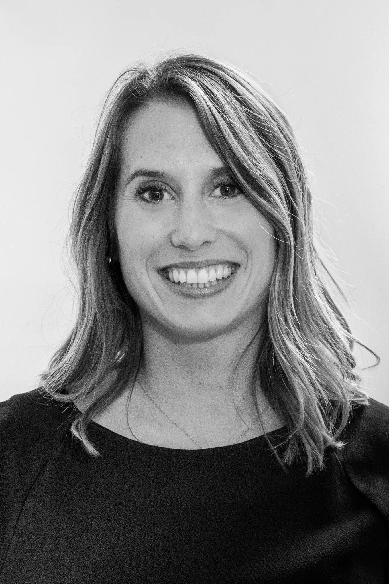 Portrait souriant d'une trentenaire aux cheveux longs, noir et blanc.