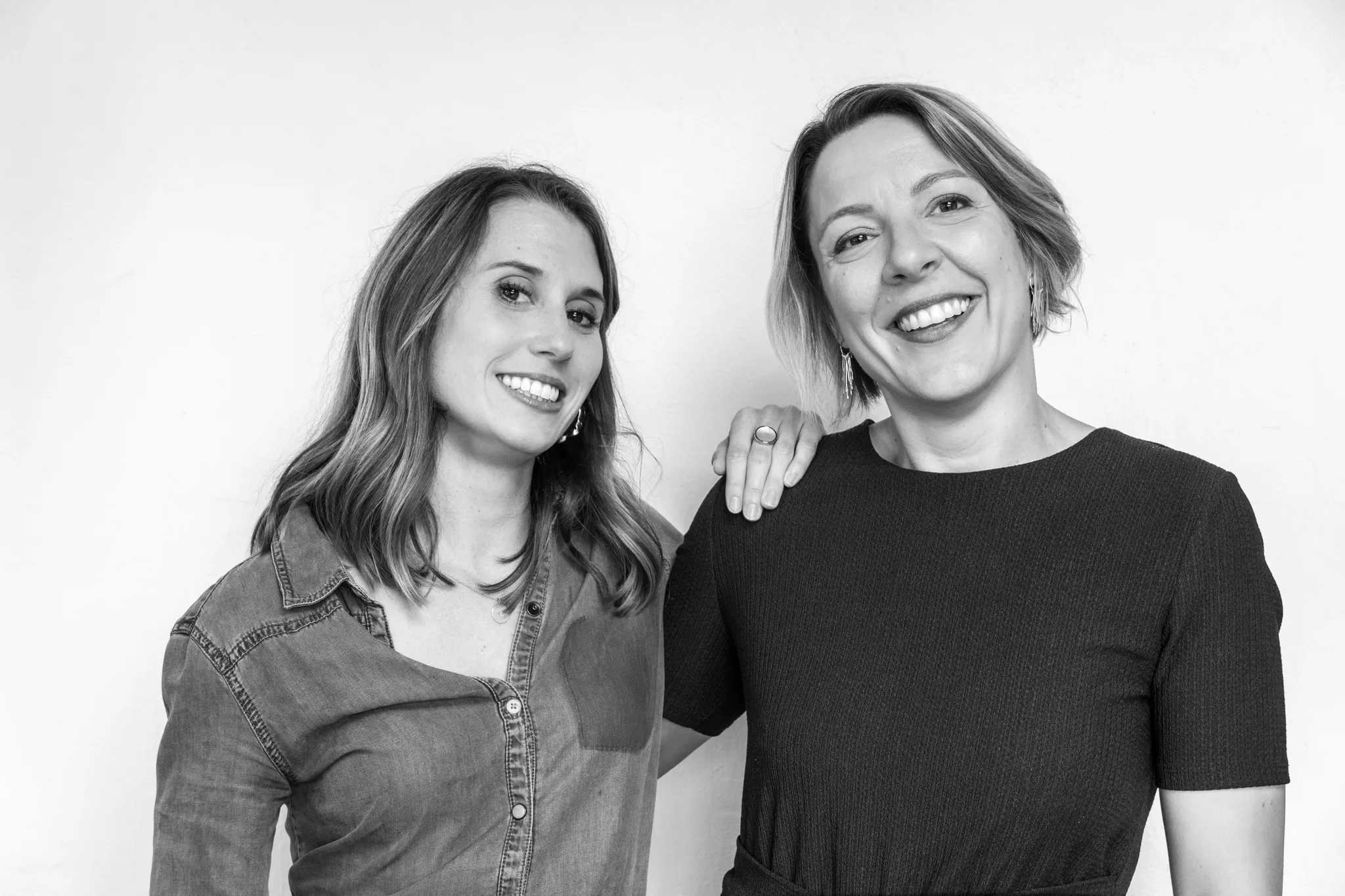 Deux collaboratrices riantes, l'une posant le bras sur l'épaule de l'autre.