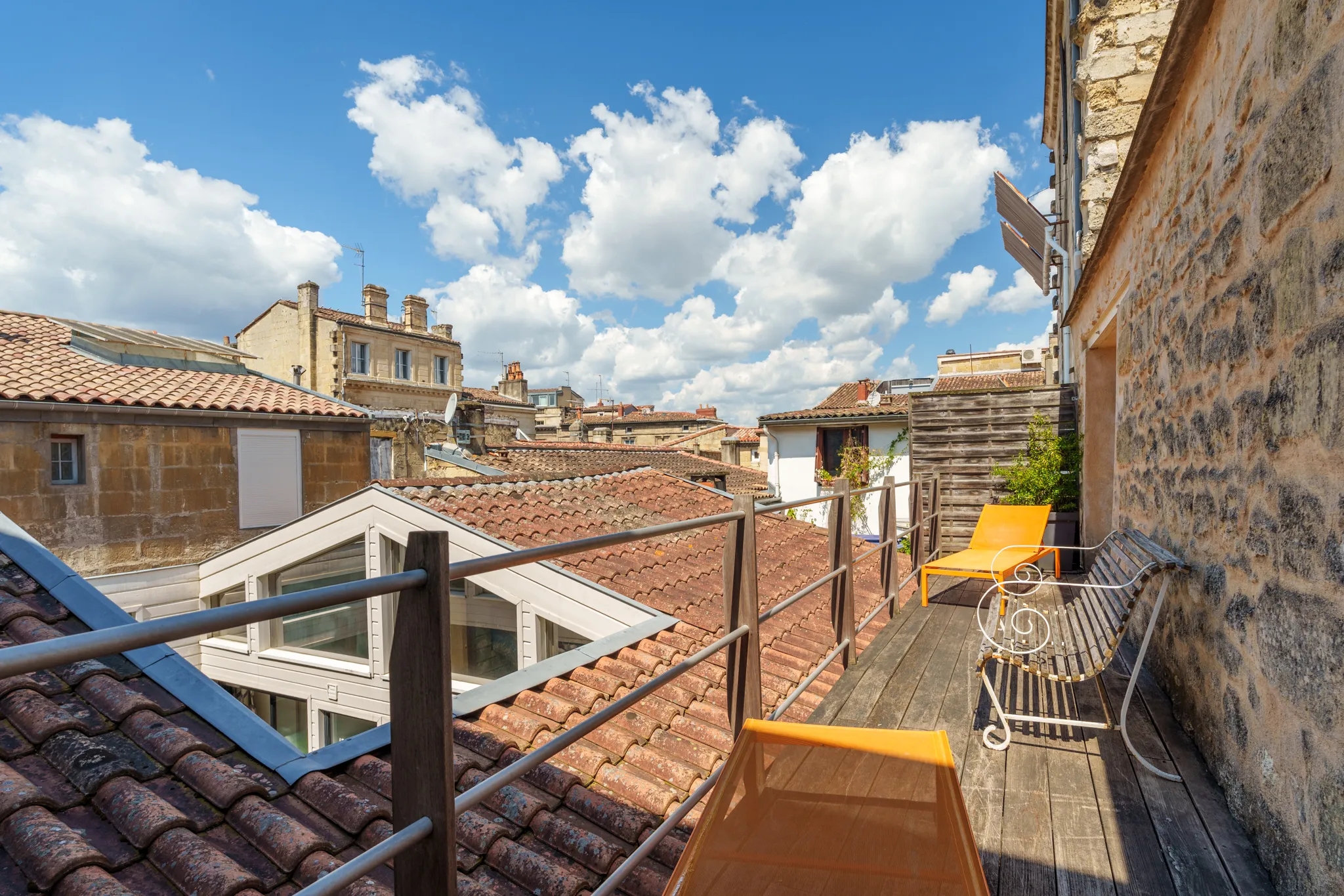Balcon avec transats jaunes, vue sur les toits