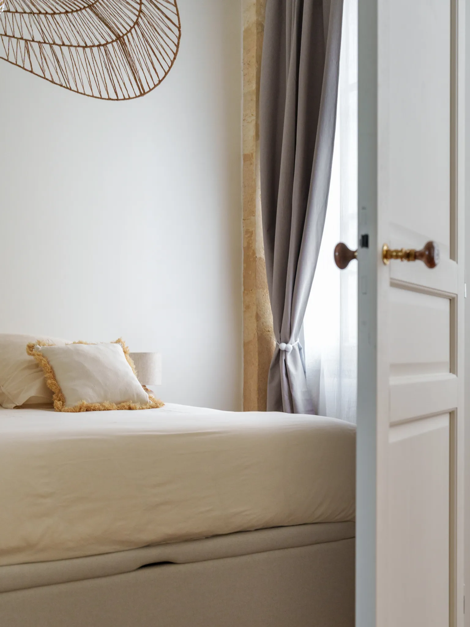 Vue intime sur une chambre écrue  à travers une porte entrouverte 