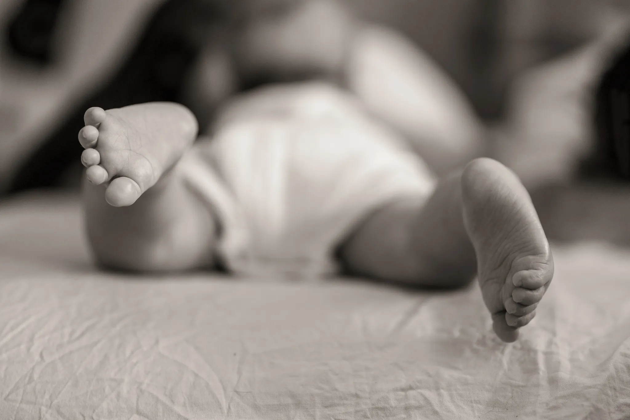 Silhouette floue bébé sur ventre en couche, gros plan sur ses pieds.