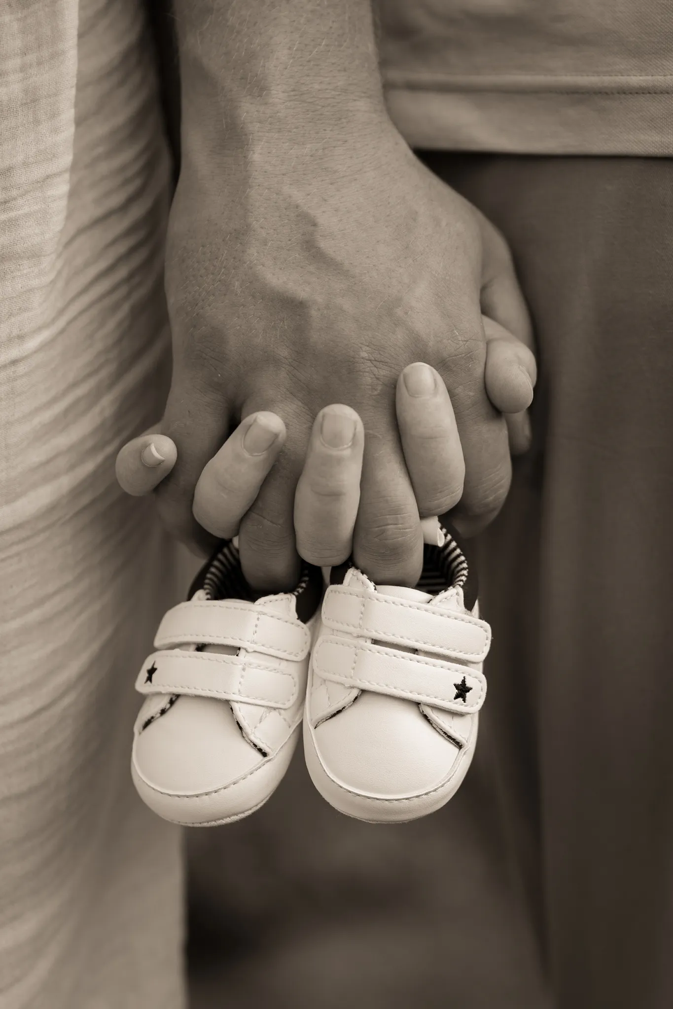 Mains jointes d'un couple, tenant des chaussures de bébé.