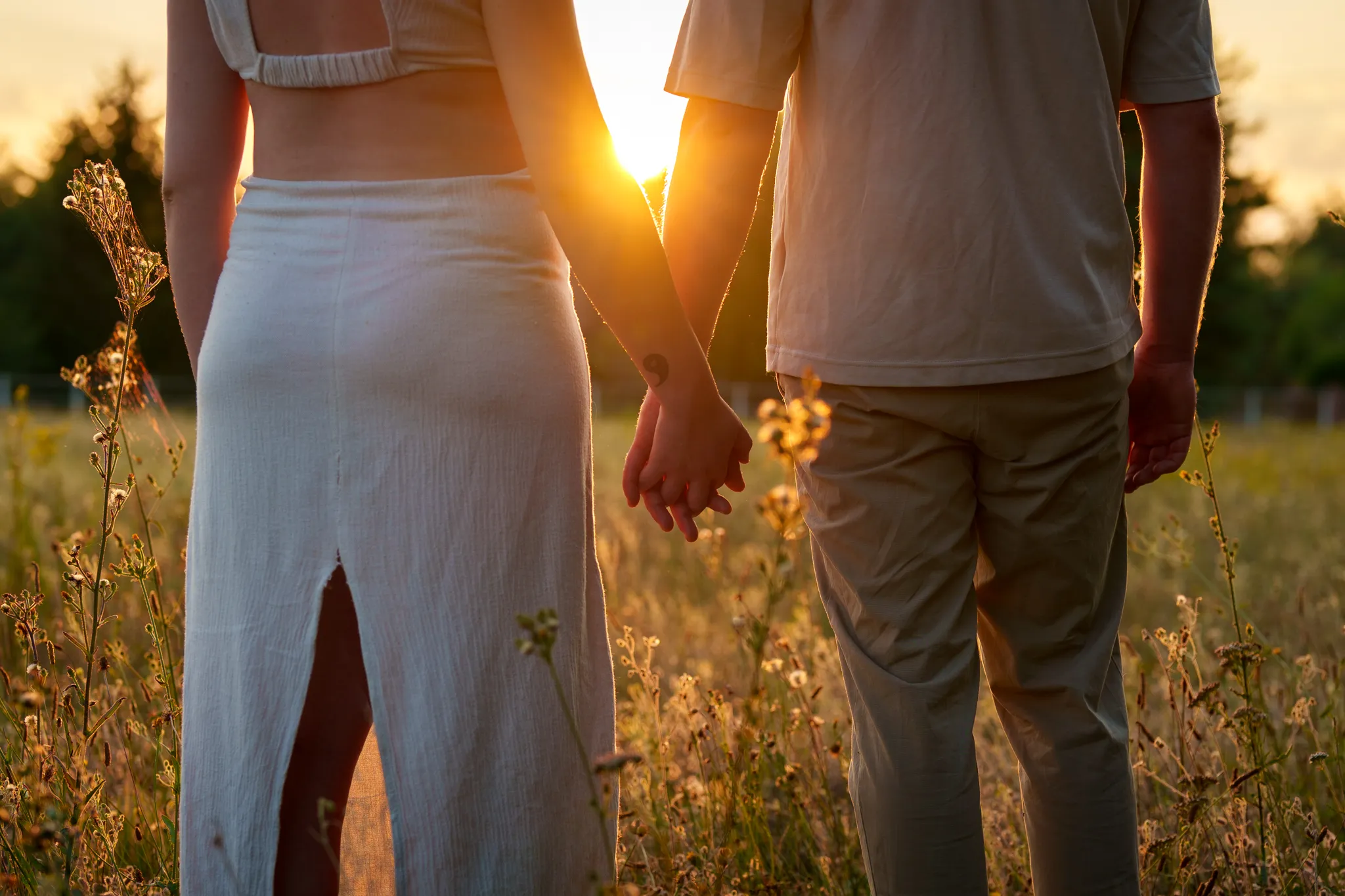 Couple qui se tienne la main, vue de dos au coucher du soleil.