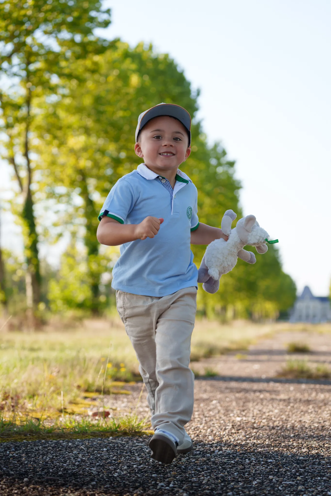 Petit garçon souriant qui court, avec son doudou à la main.