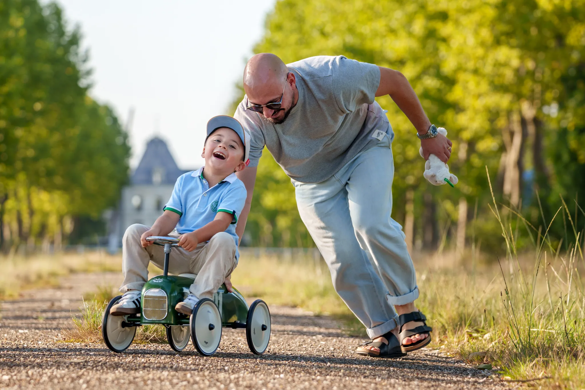Enfant riant sur sa voiture poussee par le papa