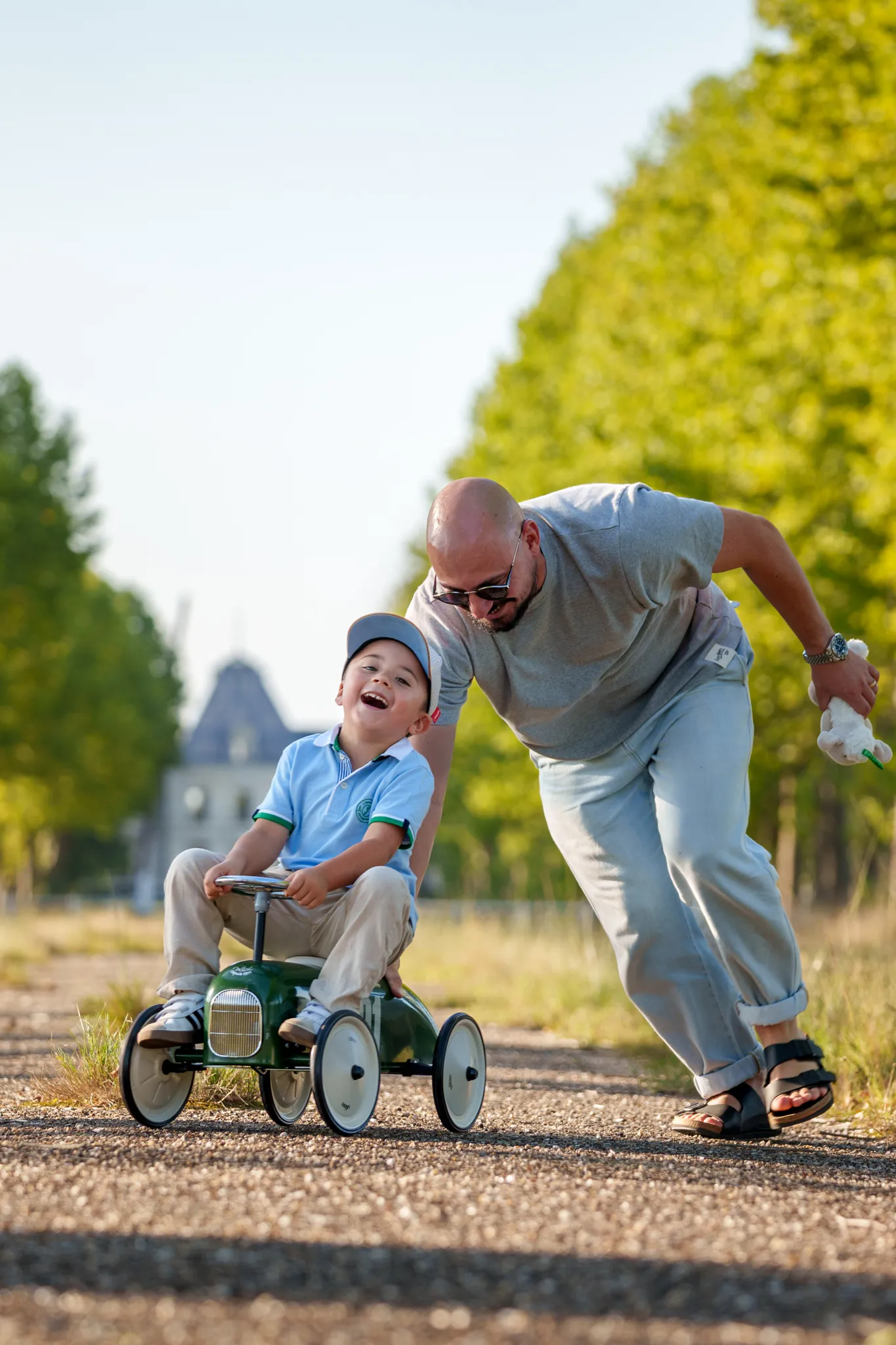 Enfant riant sur sa voiture poussee par le papa