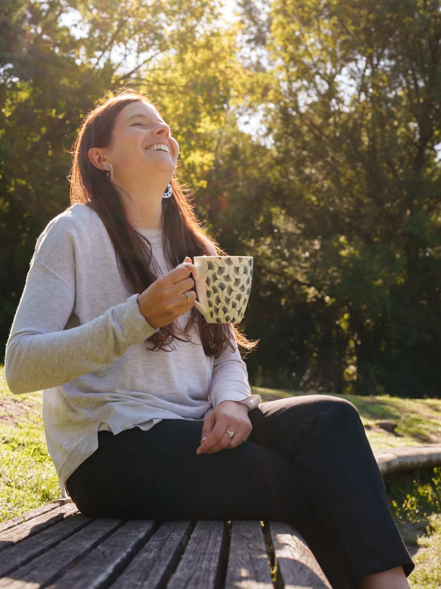 Coach seo sur un banc qui rit avec une tasse à la main.