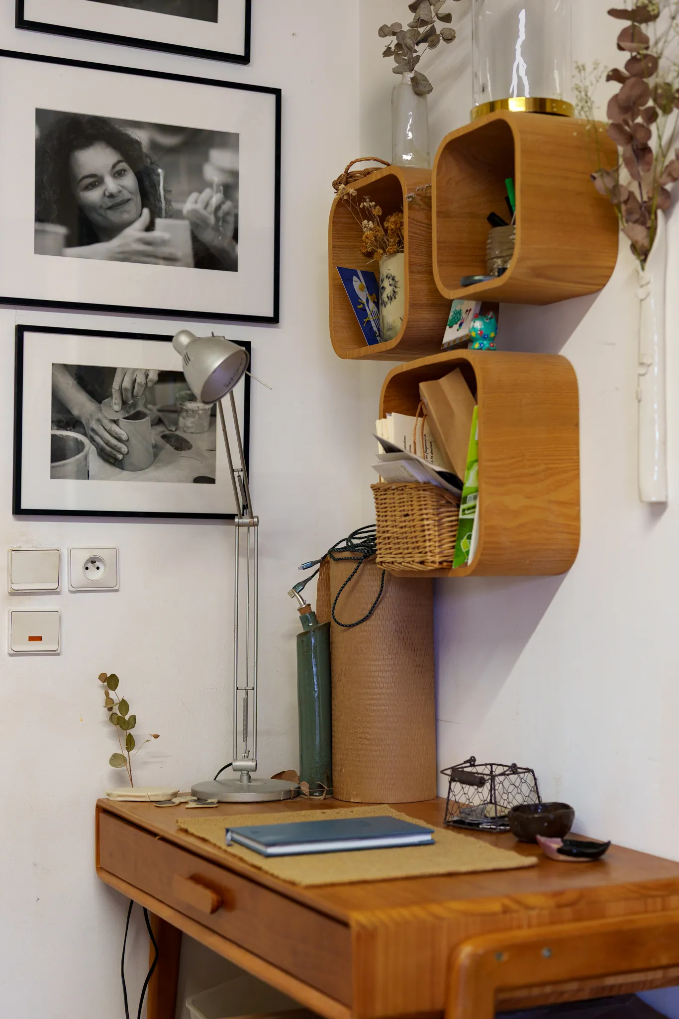 Bureau en bois dans un coin d'atelier avec des photos de l'artisane.