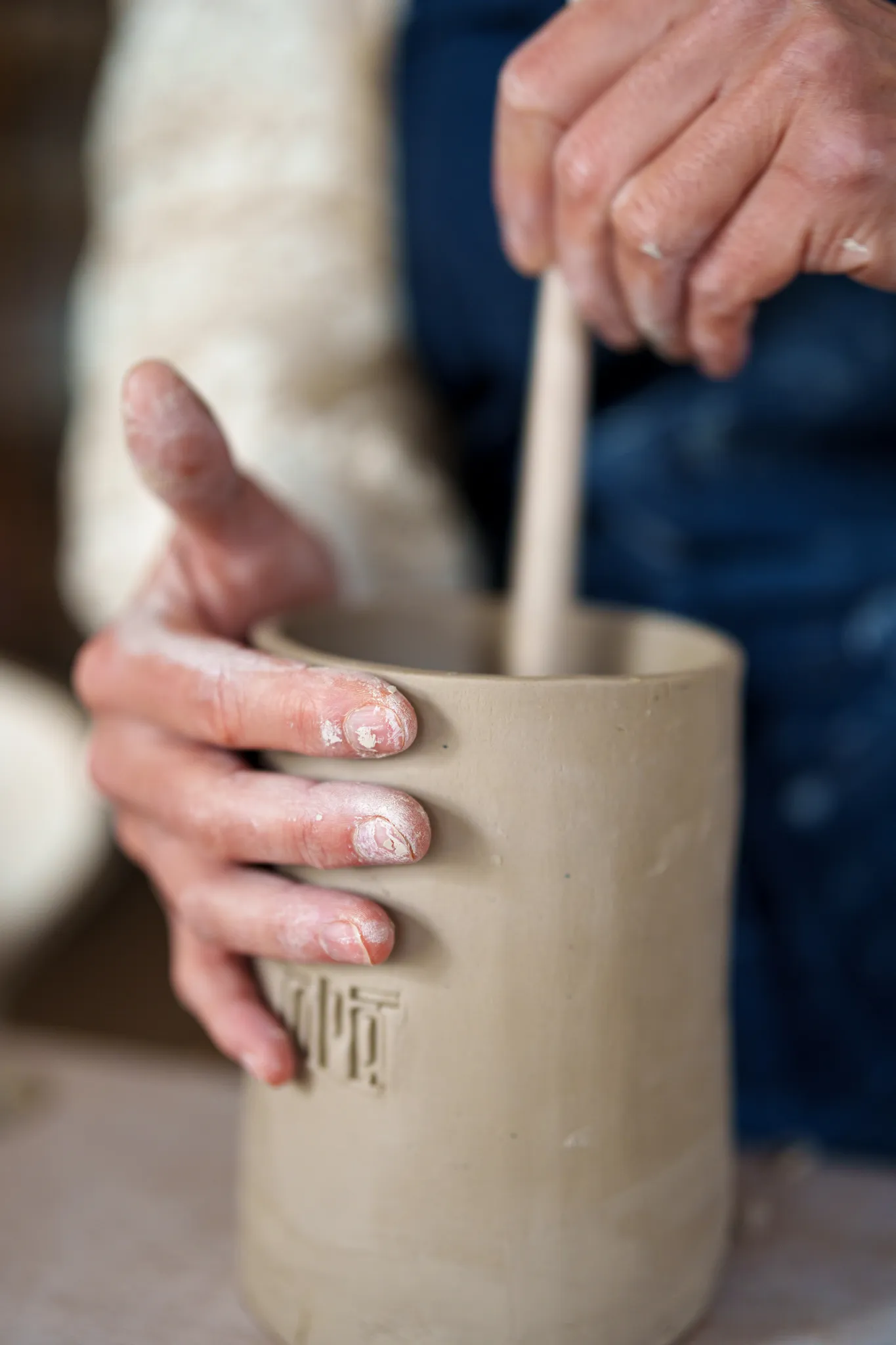 Mains d'artisane travaillant sur une poterie