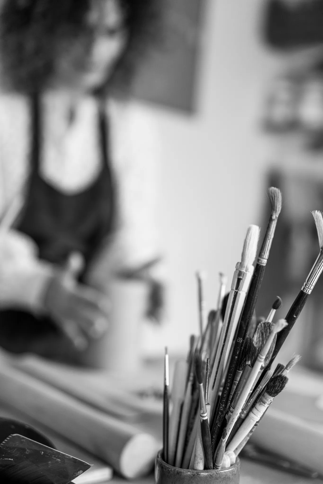 Gros plan sur pinceaux et en arrière plan artisan qui travaille.