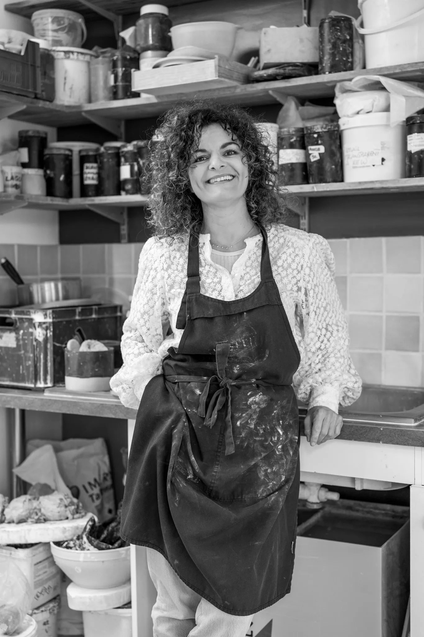 Portrait d'une céramiste souriante en tablier de travail.