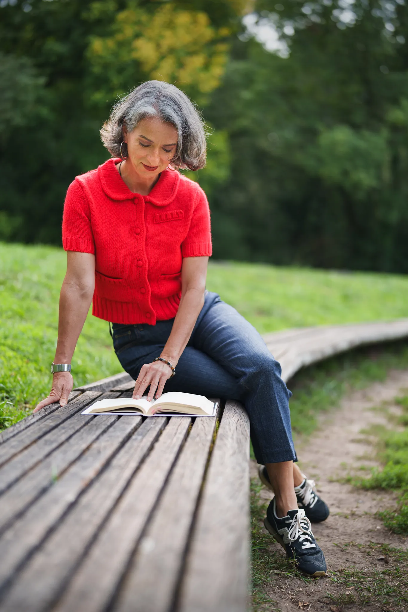Femme grisonnante, sur un banc en bois, dans un parc
