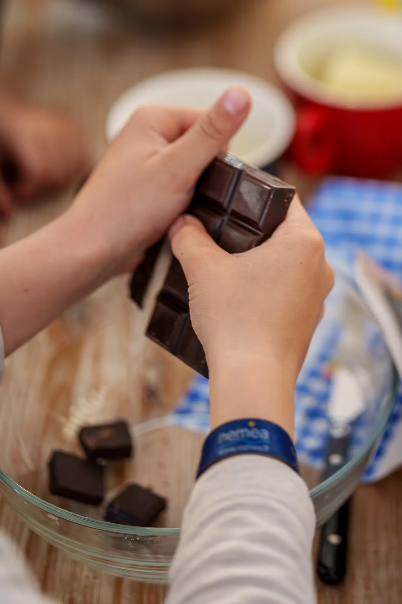 Mains d'enfants au dessus d'un saladier, qui cassent du chocolat.